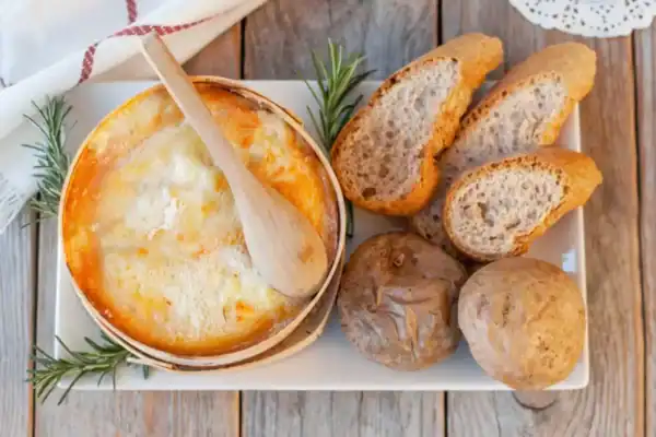 mont d'or au four fondant dans sa boîte en épicéa avec pommes de terre