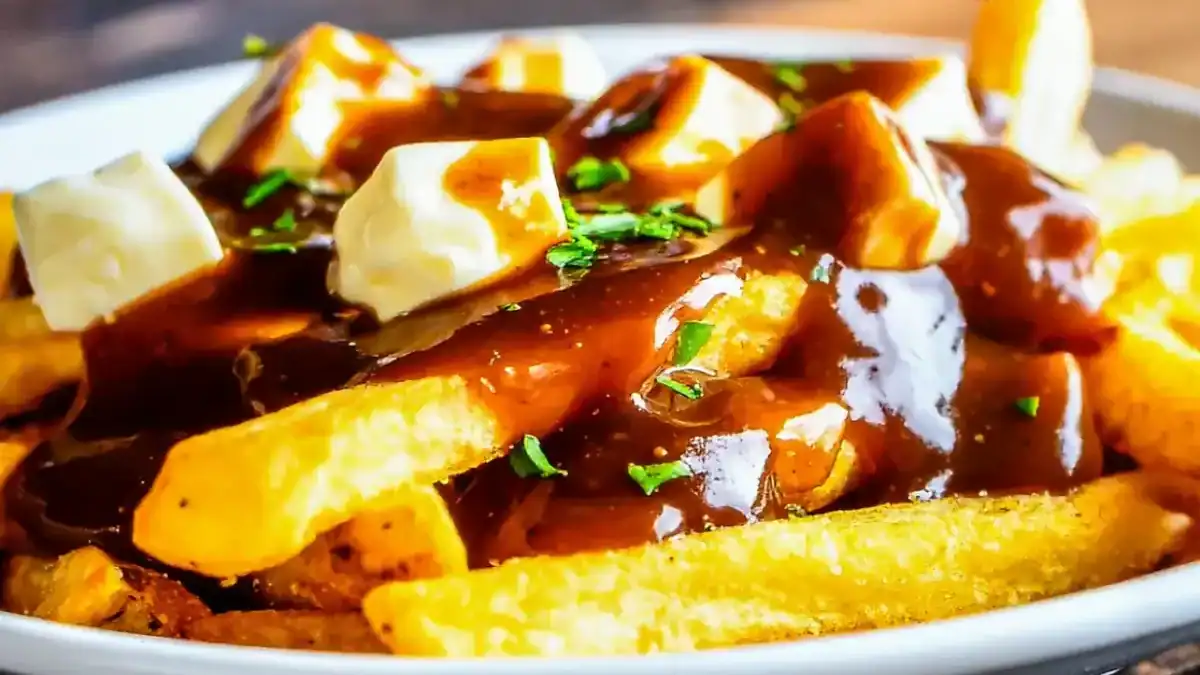 sauce brune au Thermomix versée sur des frites avec du fromage en grains dans une assiette