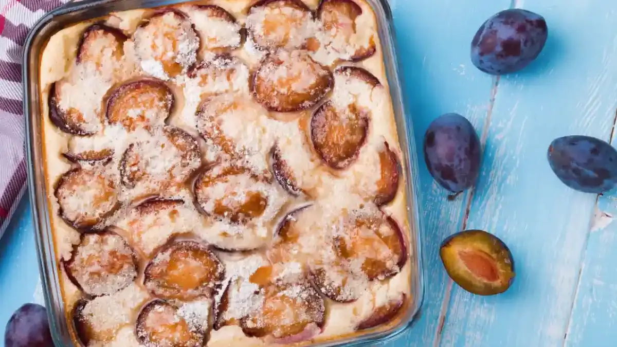 clafoutis aux prunes doré dans son plat avec des quetsches et du sucre glace