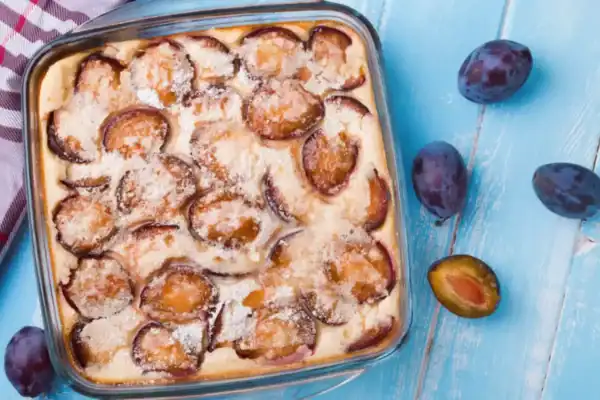 clafoutis aux prunes doré dans son plat avec des quetsches et du sucre glace